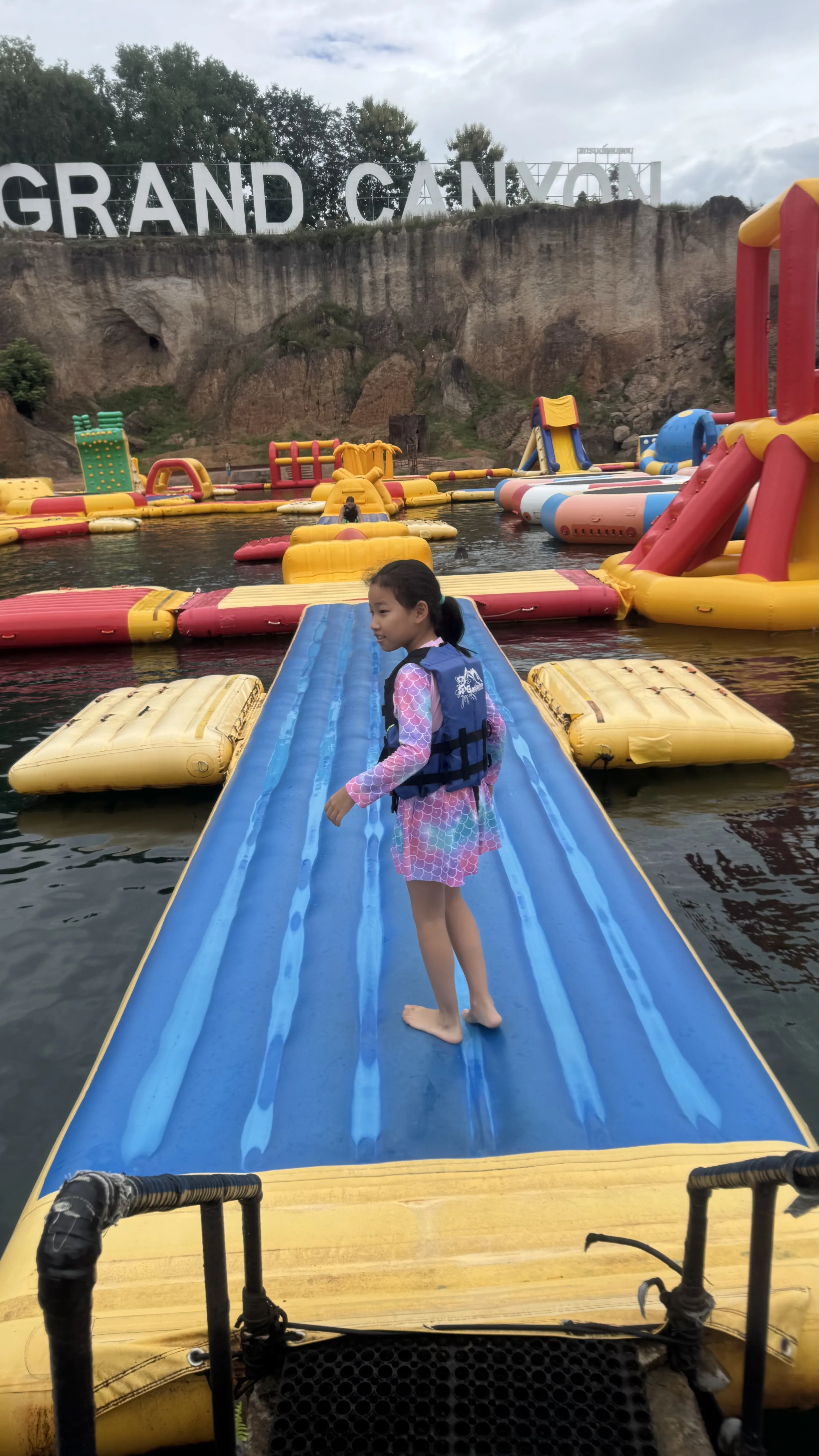 女儿站在 Grand Canyon 的蓝色充气坡道上