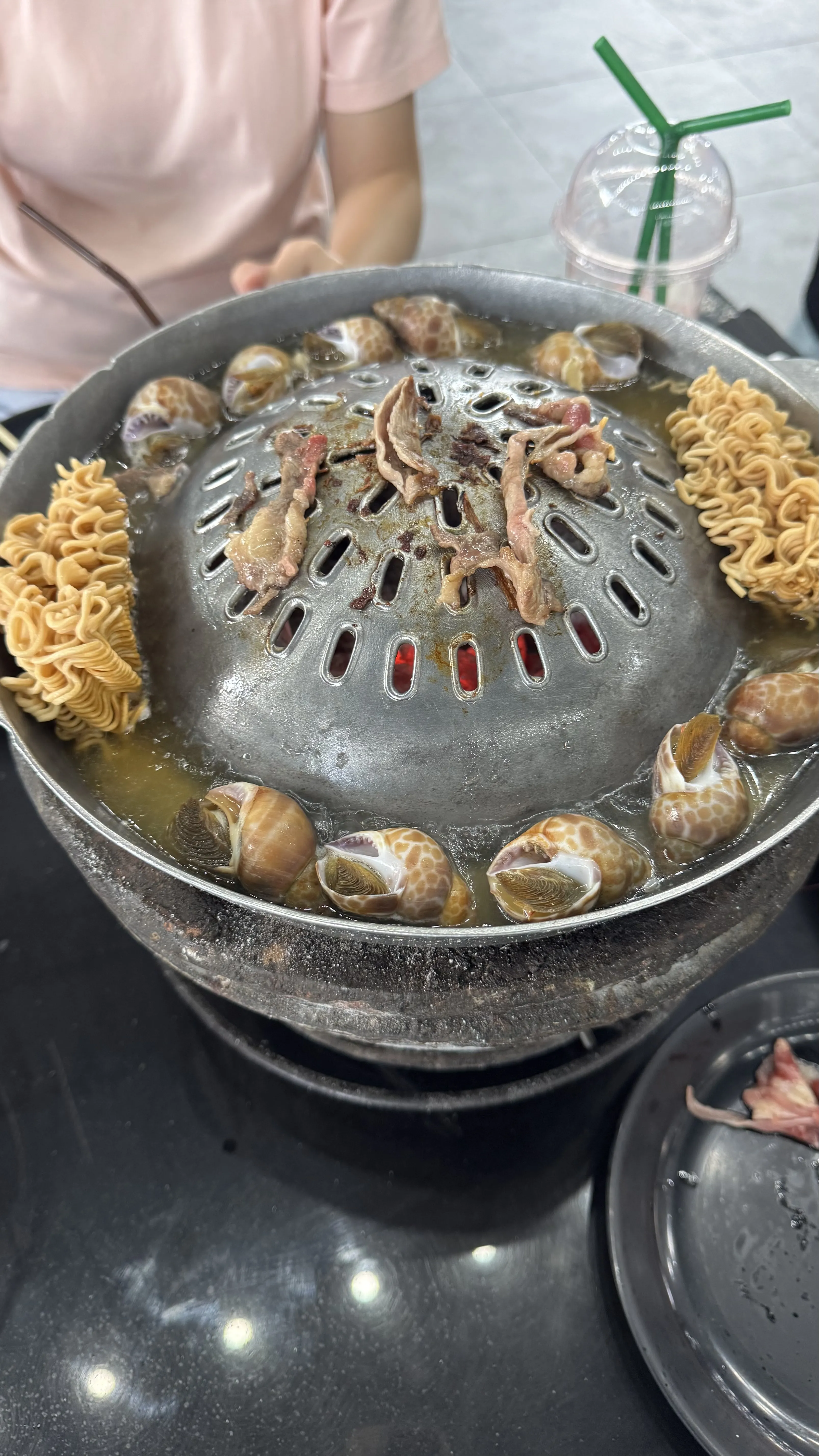 MOO OOD BBQ 桌上的 mookata 烤锅，周围煮着面和贝类